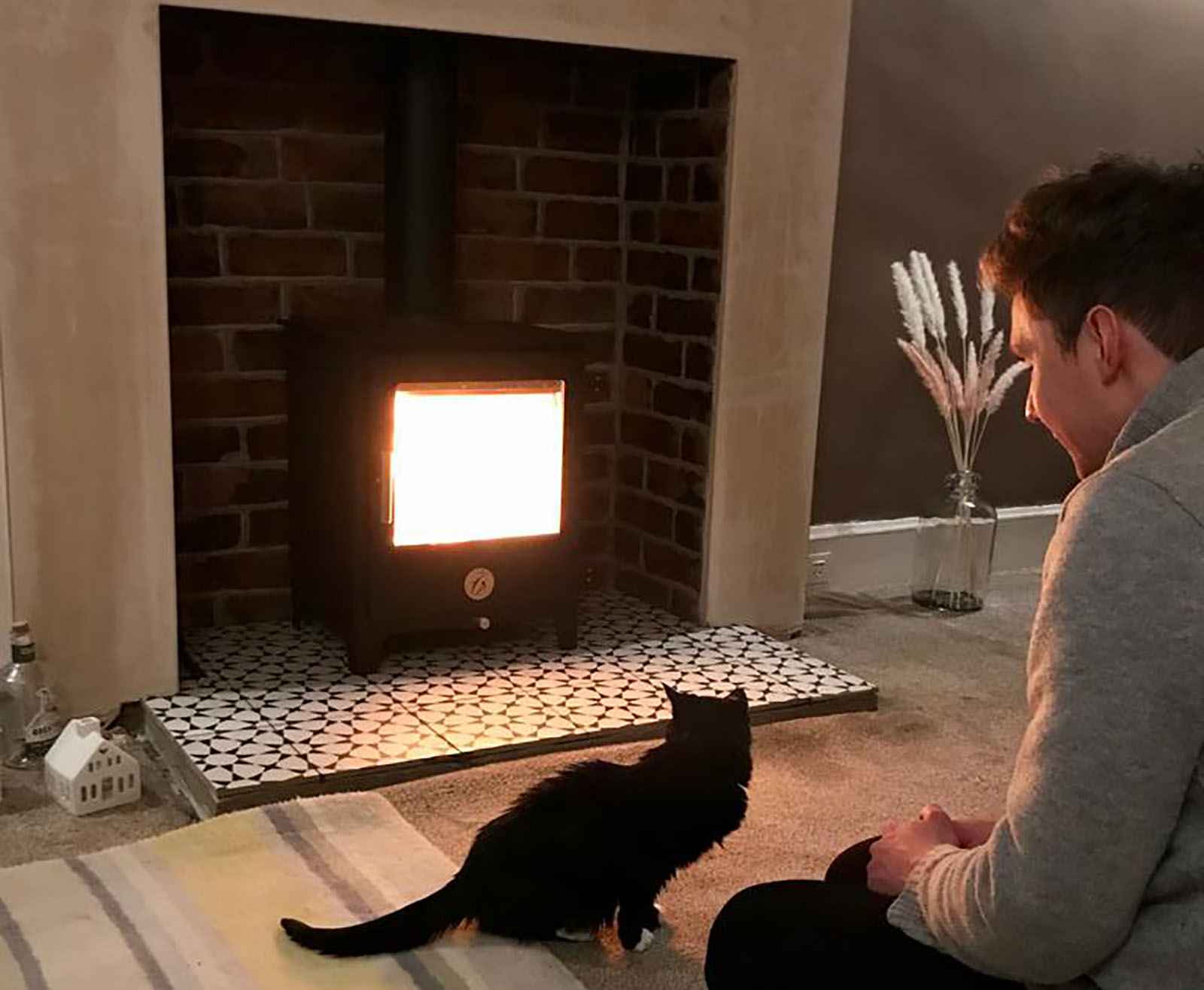 Man and cat sat in front of fire burner