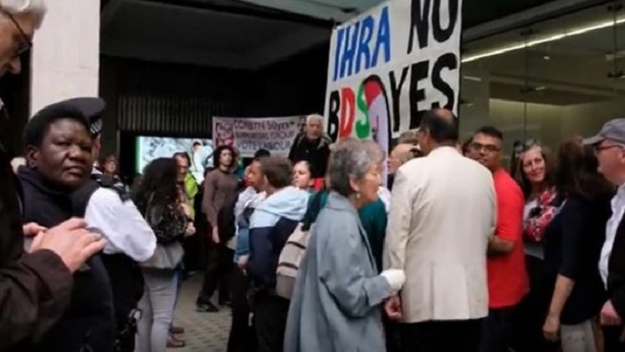 Protesting crowd with a placard 'IHRA NO, BDS YES'