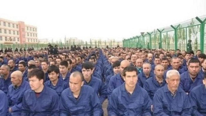 Detainees in a Xinjiang's camp sitting in rows on the ground