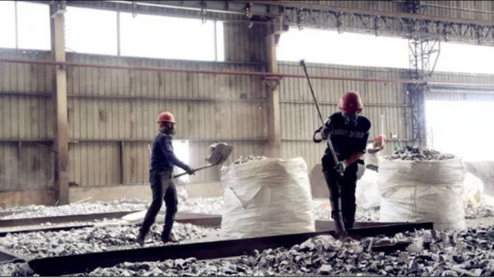 Two workers manually crushing silicon