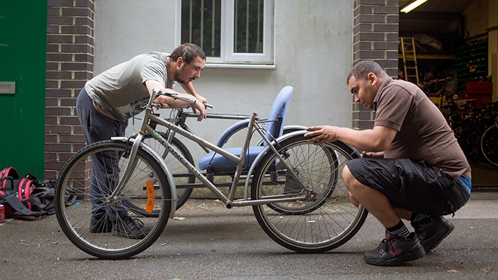 Two men fixing a bike together