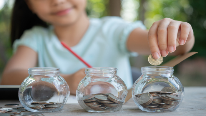 Young girl counting coins in to jars