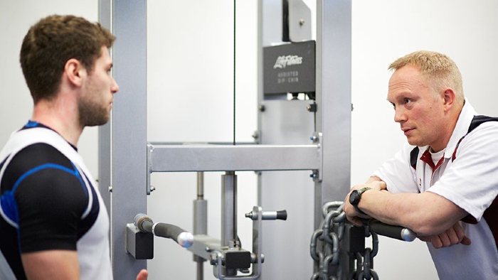 Trainer talking at weights machine