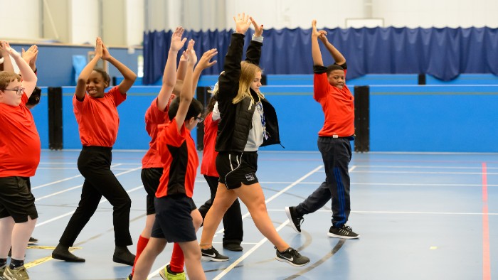 Secondary school children in a sports hall doing physical activity