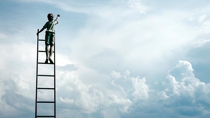 A child on a ladder, reaching upwards