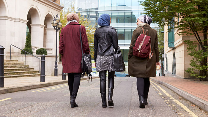 Three young women walking down a city street