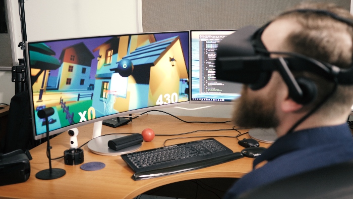 Man with VR headset on playing a game on a computer