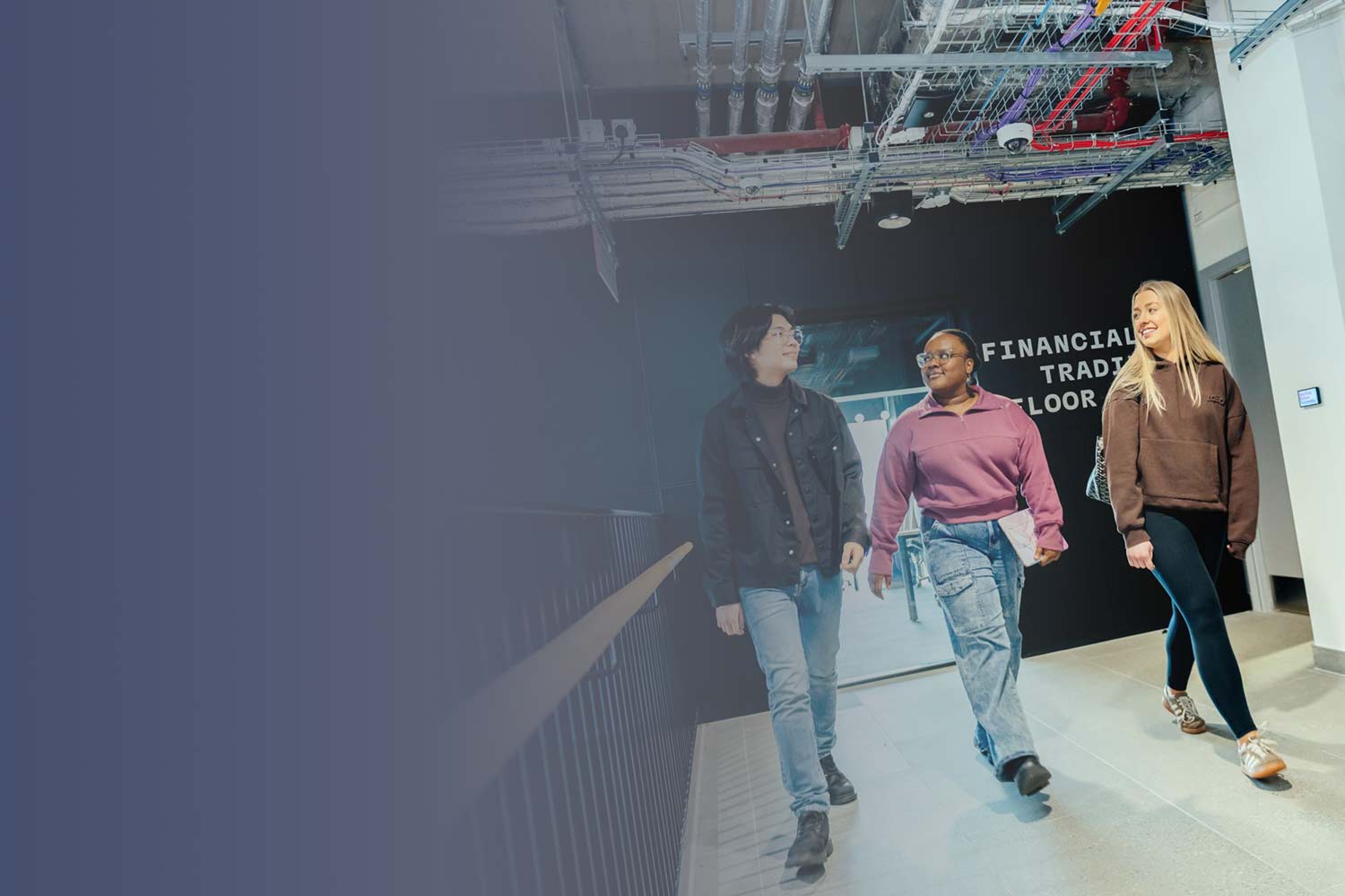 Three students walking together down a modern hallway in the Langsett building