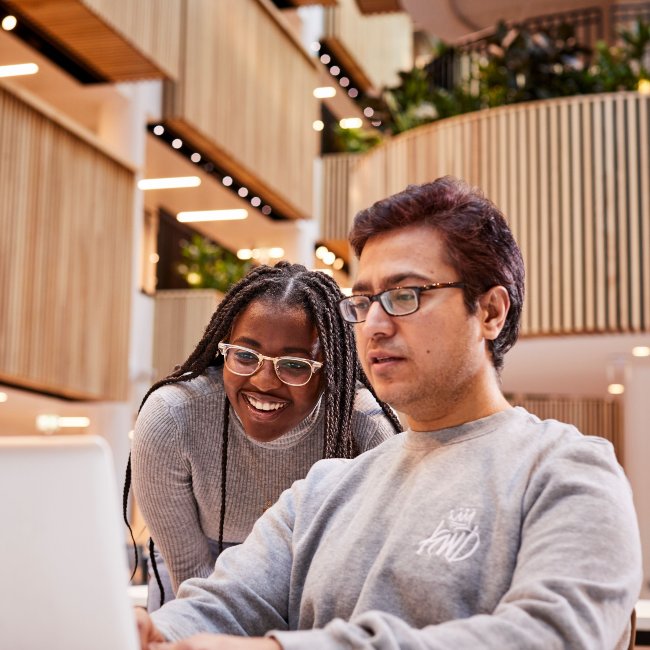 Two students sat working in front of a laptop in the Sheffield Hallam Atrium