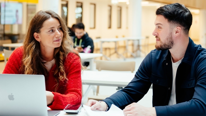 Two students working on a laptop in the atrium