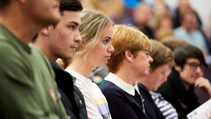 Several attendees sat amongst a crowd of people, listening to a talk at Sheffield Hallam