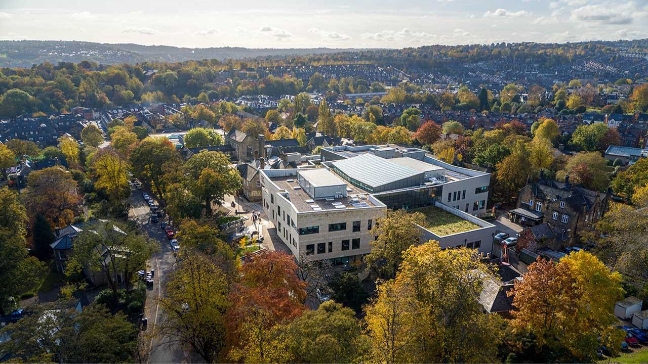 Ariel drone shot featuring the newly build Heart of Campus building at Collegiate Campus, surrounded by large trees.