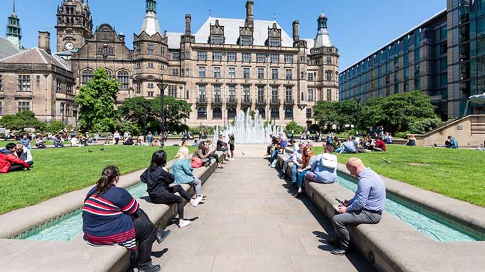 People sitting in Sheffield Peace Gardens on a sunny day