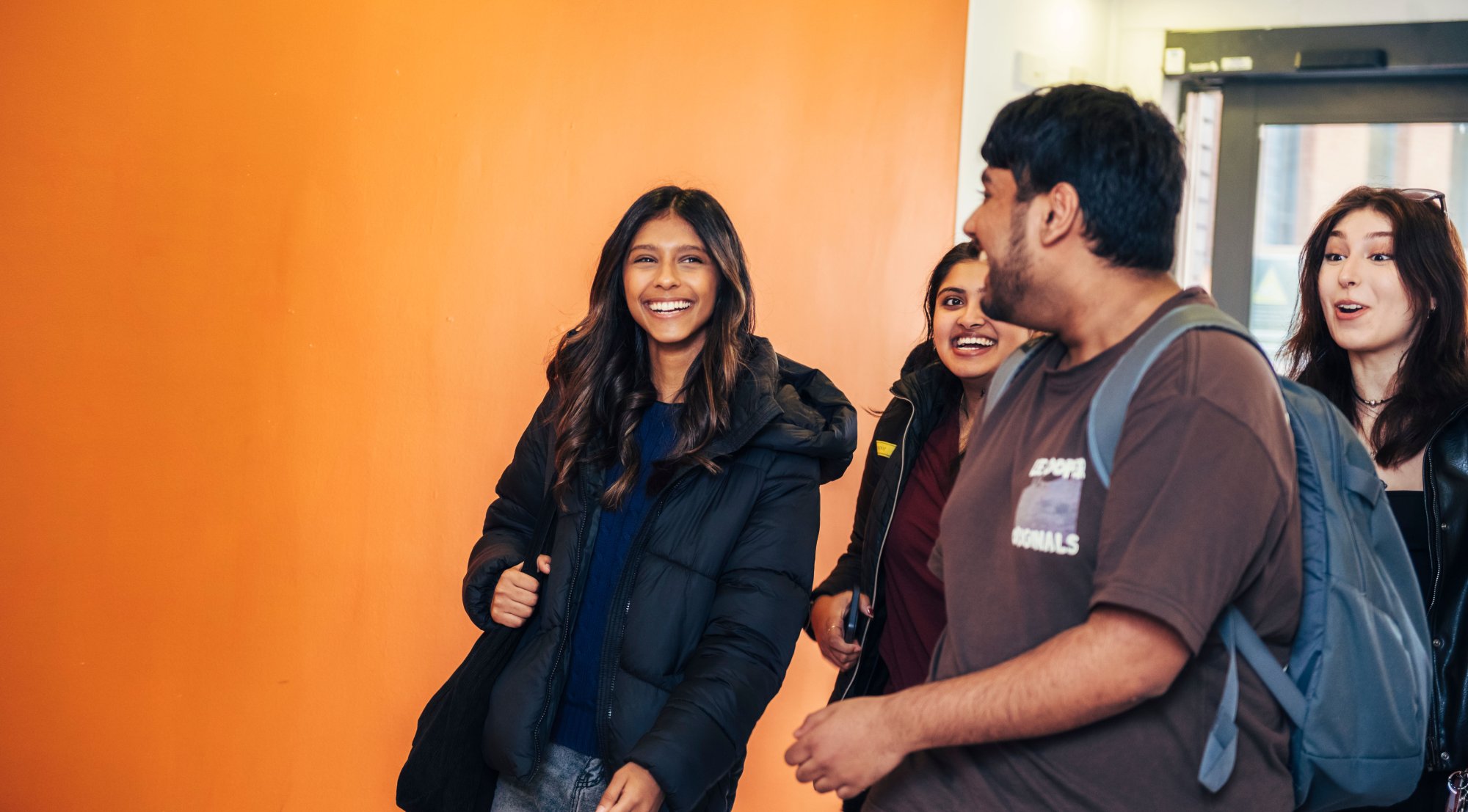 A group of students walking through student halls smiling in conversation