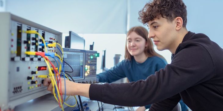 Engineering students connecting wires into a machine