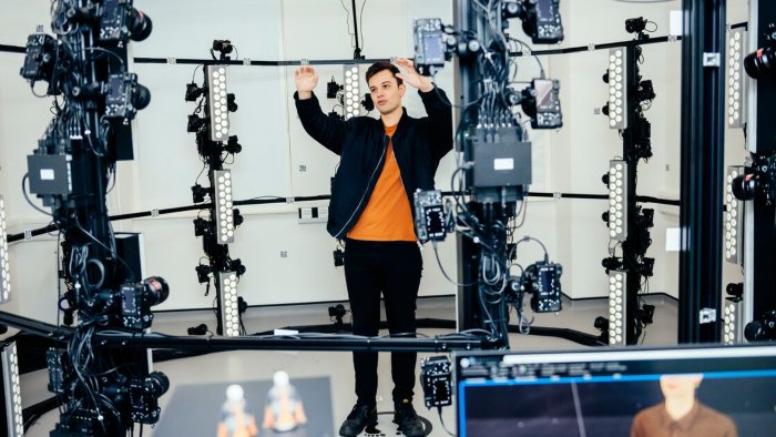 A student standing inside a circular photogrammetry setup surrounded by cameras and lights.