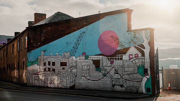 Mural of old industrial buildings and a crane – by Jo Peel, on Alma Street, Sheffield
