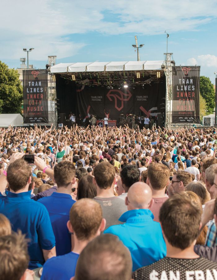 A large crowd of people at the Tramlines music festival facing a stage on Devonshire Green in Sheffield City Centre.