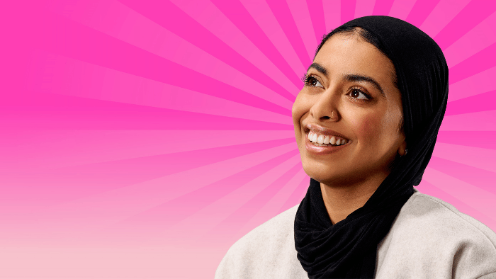 A smiling Hallam student set against a pink background.