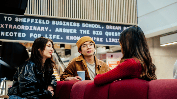 Three students socialise outside a café in Sheffield Hallam's Redmires Building.