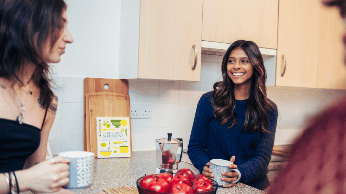 Two students chatting over coffee in a kitchen area of student halls.