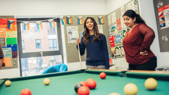 Two Hallam students play pool in an accommodation social area.