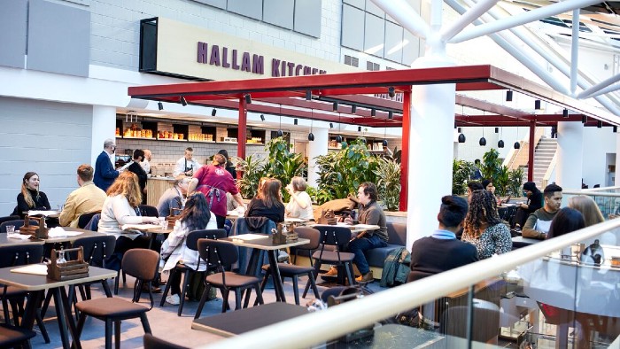 A mixture of students and academics sat eating and drinking at Hallam Kitchen