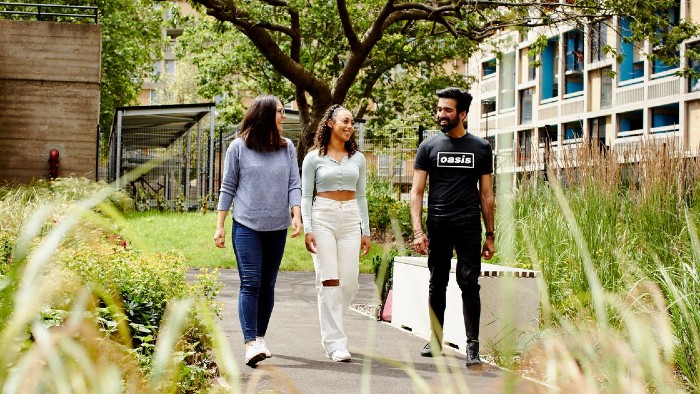 Three students in conversation walking from their accommodation