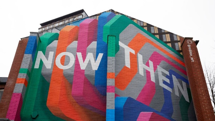 A mural on the side of a building which states the words Now Then in large letters.