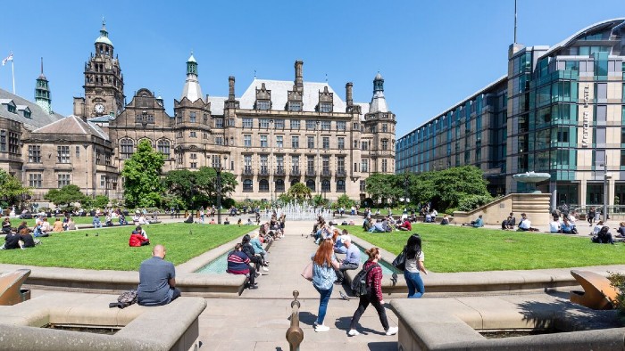 People sitting in and walking through the Sheffield Peace Gardens on a sunny day