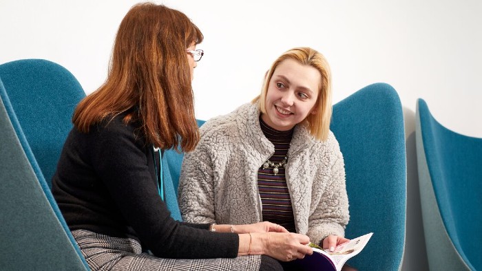 A student sat on a sofa in discussion with a Sheffield Hallam member of staff.