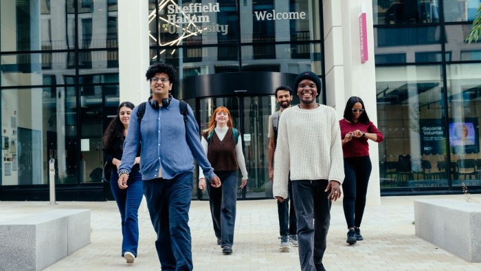 A group of people walking out of a building into Hallam Green at the Sheffield Hallam city campus.