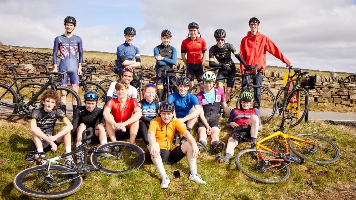 A group of Sheffield Hallam student cyclists sitting and standing on grass with their bikes in the Peak District.