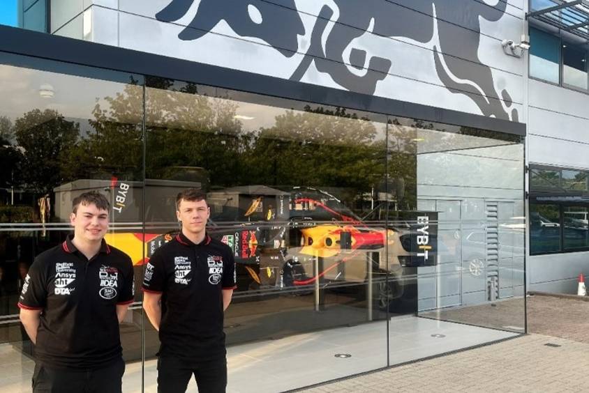 Two students stand in front of Red Bull Racing building