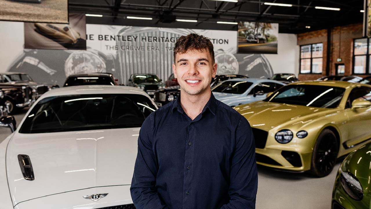 Kasper in a shirt stood in front of Bentley Vehicles