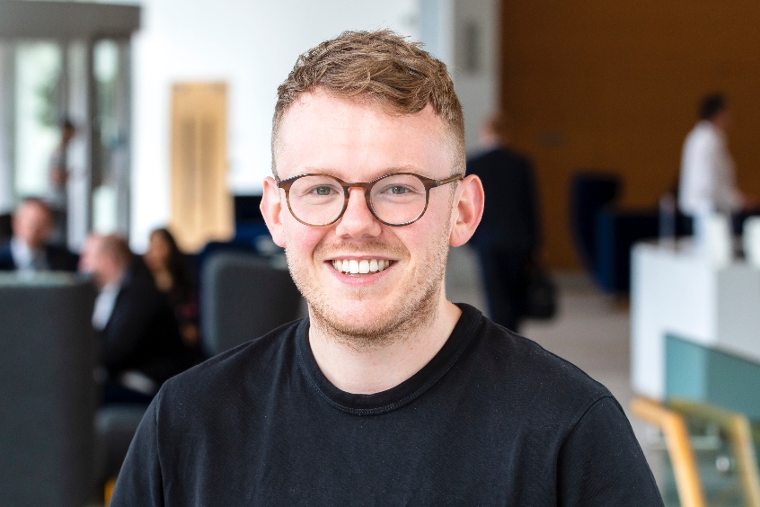 Headshot of Cameron wearing glasses and a black top.