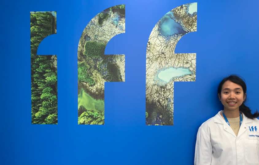 Student in white lab coat standing in front of blue background with IFF logo.