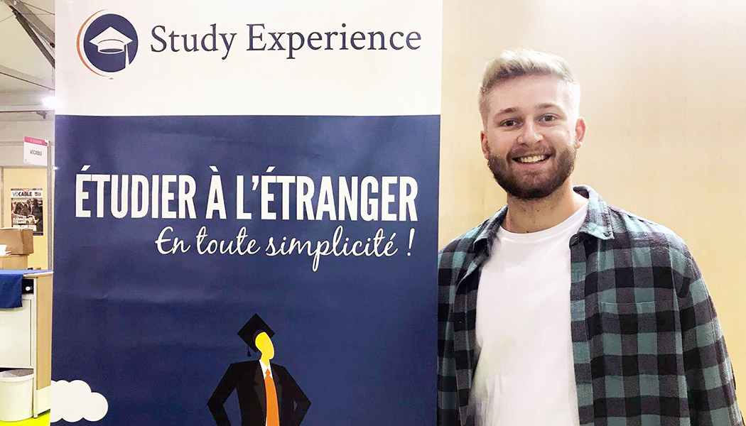 James Gallagher standing for a photo next to the study experience banner