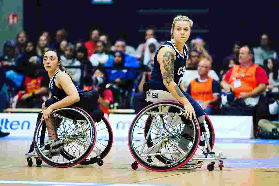 Two women on court playing wheelchair basketball.