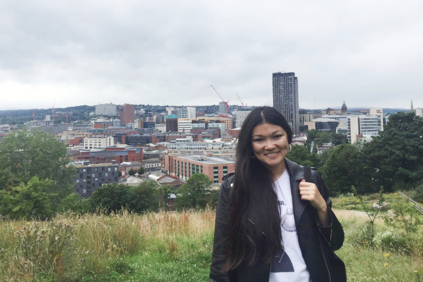 Girl stood in front of Sheffield cityscape smiling.