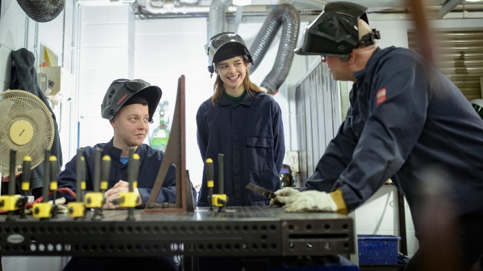 Two students discussing work with their tutor in a workshop