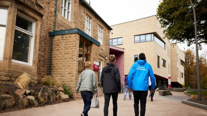 A student ambassador taking visitors on a tour of collegiate campus.