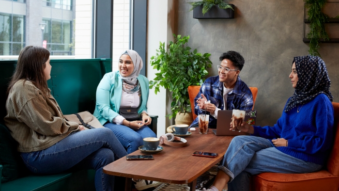A group of students sat around a table in a cafe chatting.