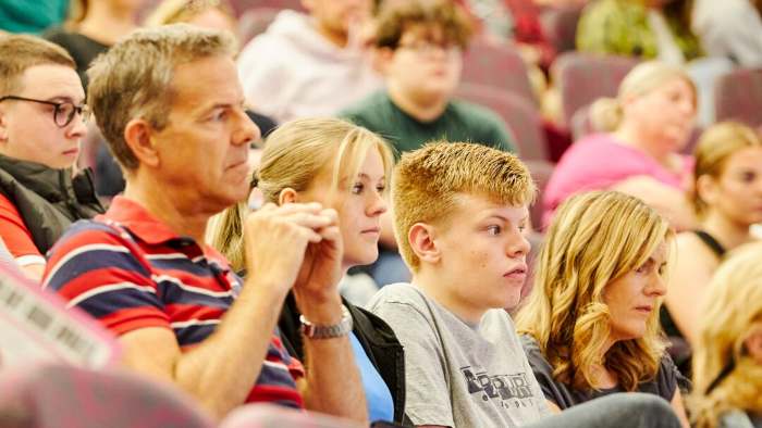 A student sits with their family in a lecture crowded theatre 
