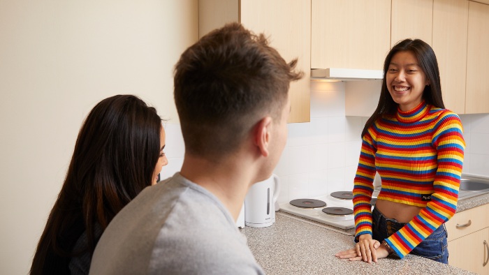 Three students talking in their kitchen