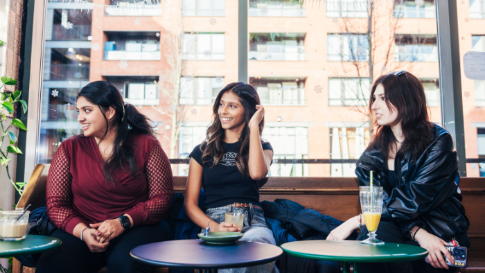 Three Sheffield Hallam students socialising in a cafe in Sheffield city centre.
