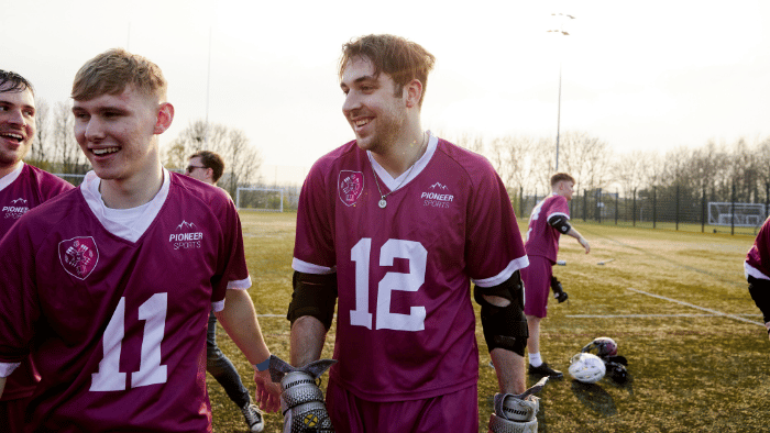 Two lacrosse players walk off the pitch smiling after playing a game for Sheffield Hallam.