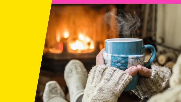 Photo of someone with a cup of cocoa by a log fire