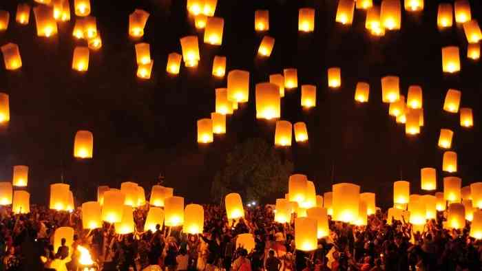 A photo of lit floating lanterns being released into a dark nights sky.