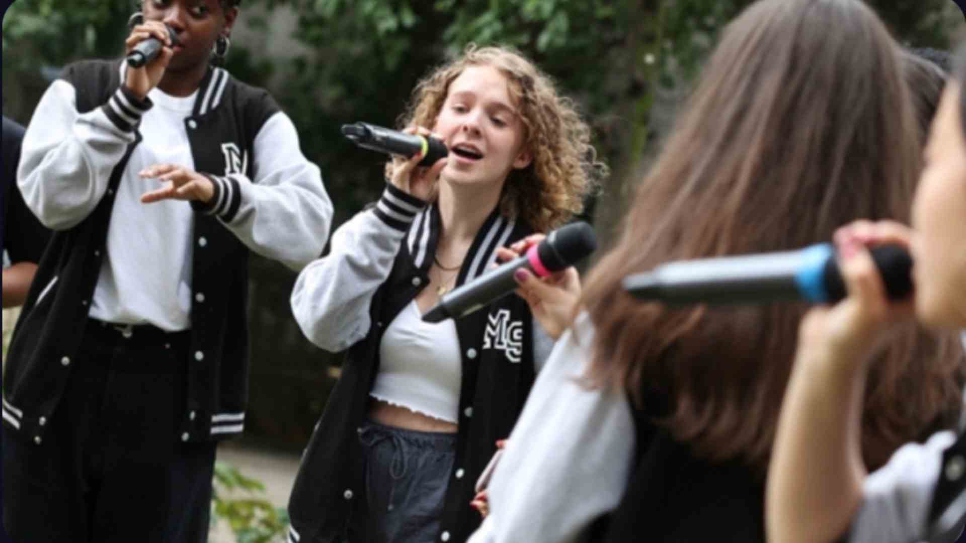 Photo of a group of people with microphones singing outside